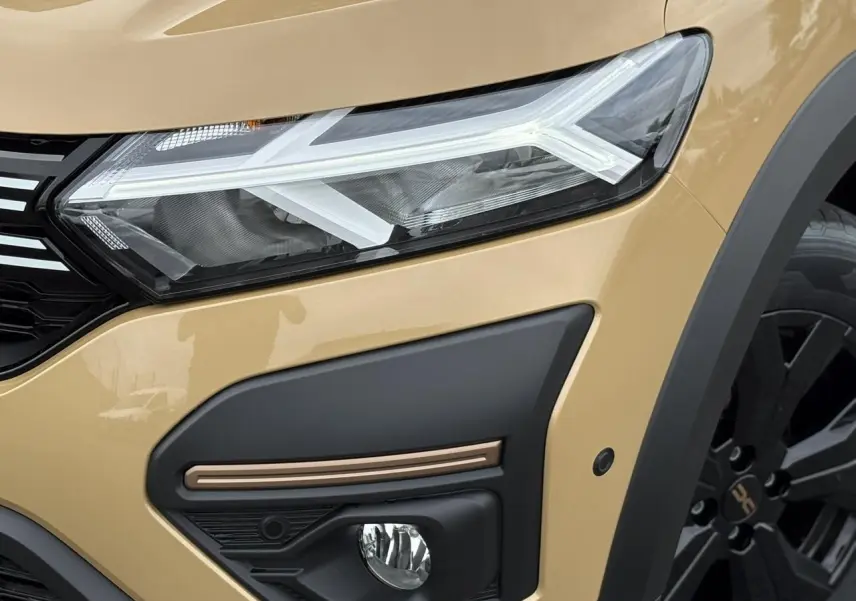 Gros plan sur l'avant droit beige Safari du Dacia Sandero Stepway 2025, avec phares LED et jante noire distinctive.
