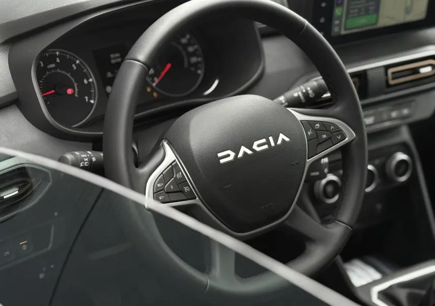 Vue rapprochée du volant noir de la Dacia Sandero Stepway 2025 avec commandes intégrées et tableau de bord numérique.