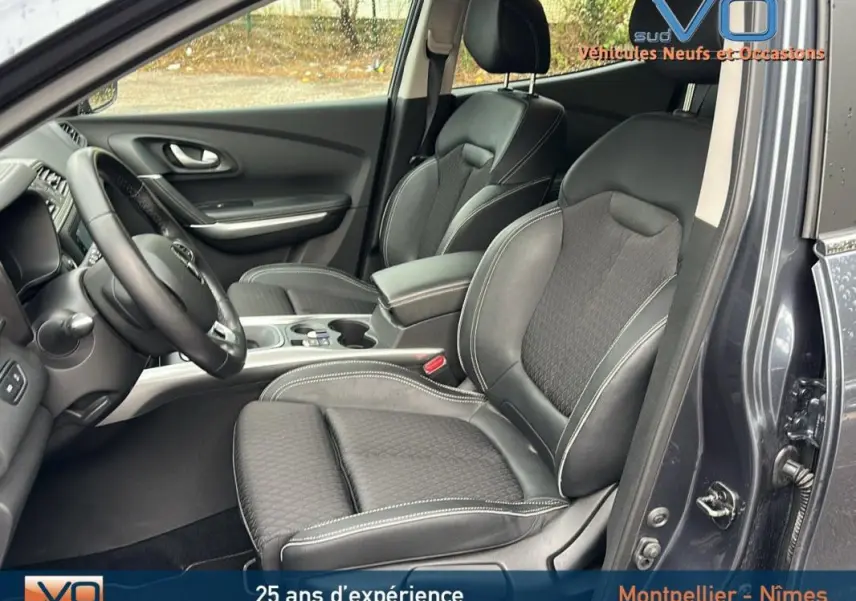 Vue intérieure côté conducteur du Renault Kadjar gris 2019, sièges cuir noirs avec surpiqûres blanches et console centrale.