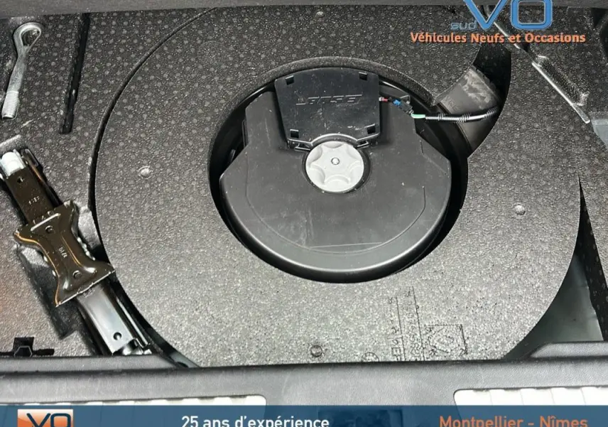 Vue rapprochée du compartiment de rangement sous le coffre du Renault Kadjar gris, montrant la roue de secours et les outils.