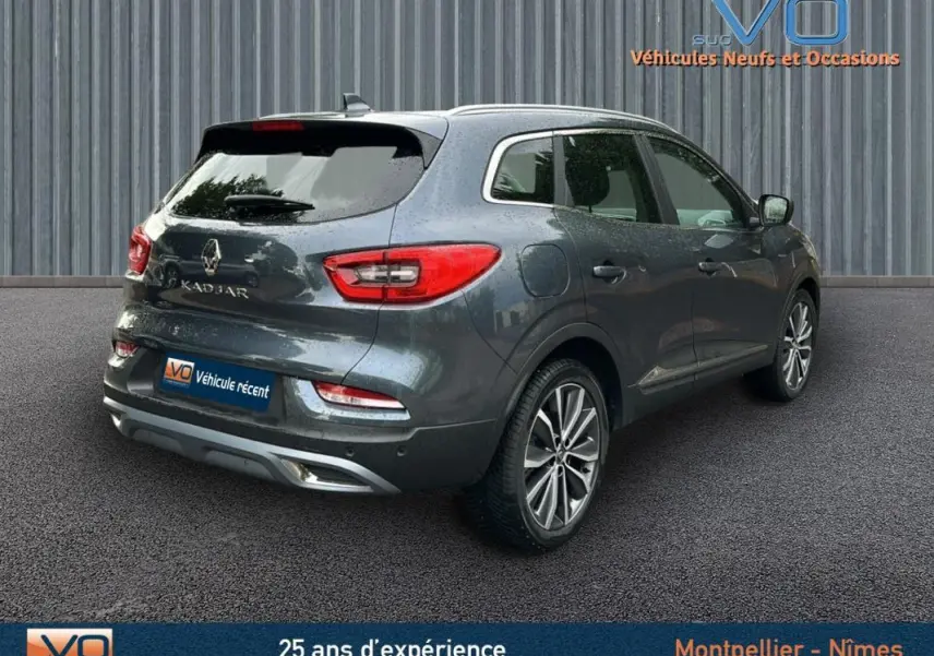 Vue 3/4 arrière droite d'un Renault Kadjar gris 2019 avec jantes alliage 18 pouces et barres de toit visibles