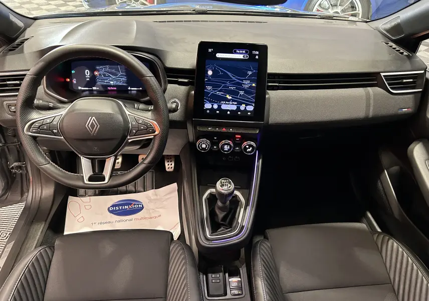 Vue intérieure frontale de la Renault Clio V TCe 90 Esprit Alpine, tableau de bord gris avec écran tactile central et volant multifonction.