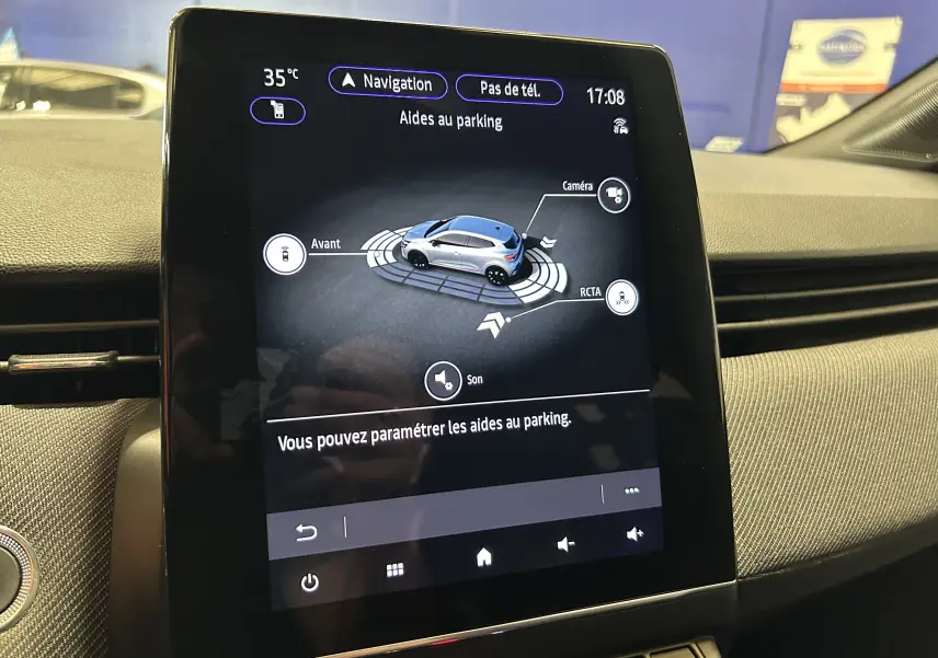 Écran tactile intérieur de Renault Clio V gris schiste montrant l'interface d'aides au parking avec vue 3D du véhicule.