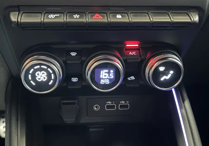 Vue rapprochée de la console centrale de la Renault Clio V gris schiste, avec commandes climatisation et ports USB visibles.
