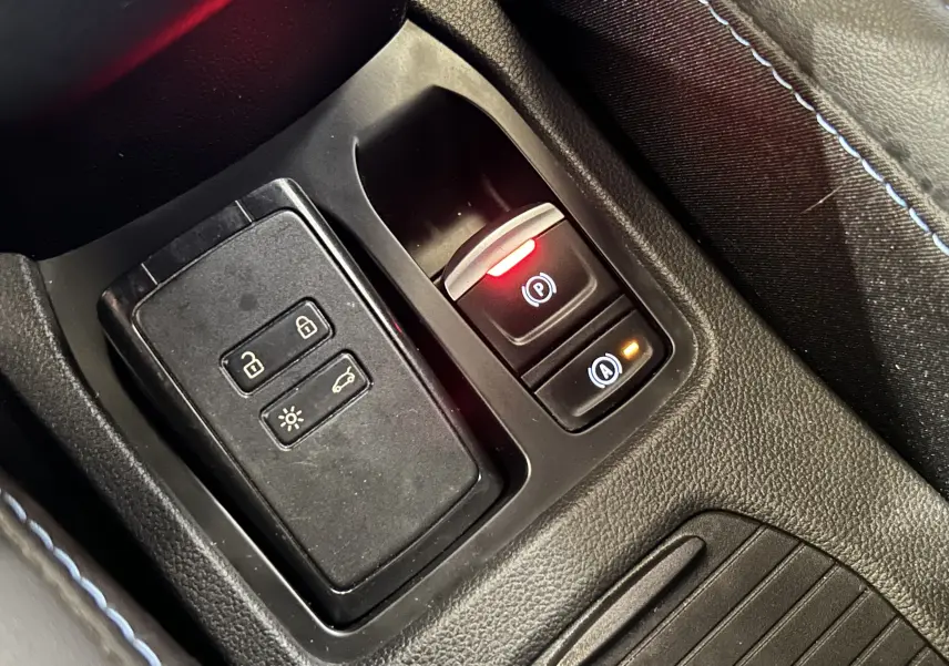 Gros plan sur la console centrale noire avec commandes électroniques et coutures bleues du Renault Clio V Gris Schiste.