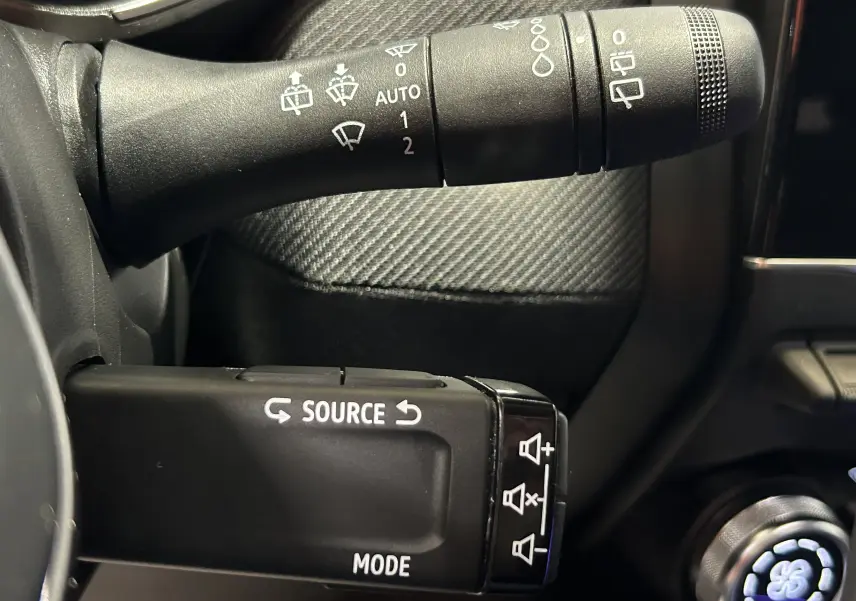 Gros plan sur les commandes de lève-glace et essuie-glace dans l’habitacle noir du Renault Clio V gris schiste.