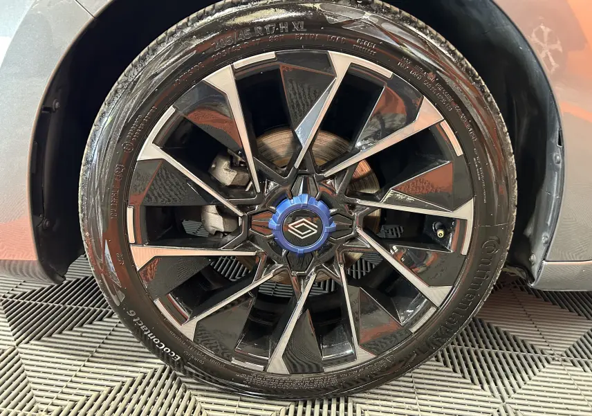 Gros plan sur la jante avant droite noire et argentée de la Renault Clio V Gris Schiste avec logo Alpine bleu au centre.