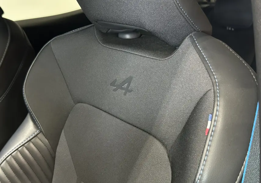 Gros plan sur le siège avant noir de la Renault Clio V TCe 90 Esprit Alpine avec logo Alpine et surpiqûres bleues.