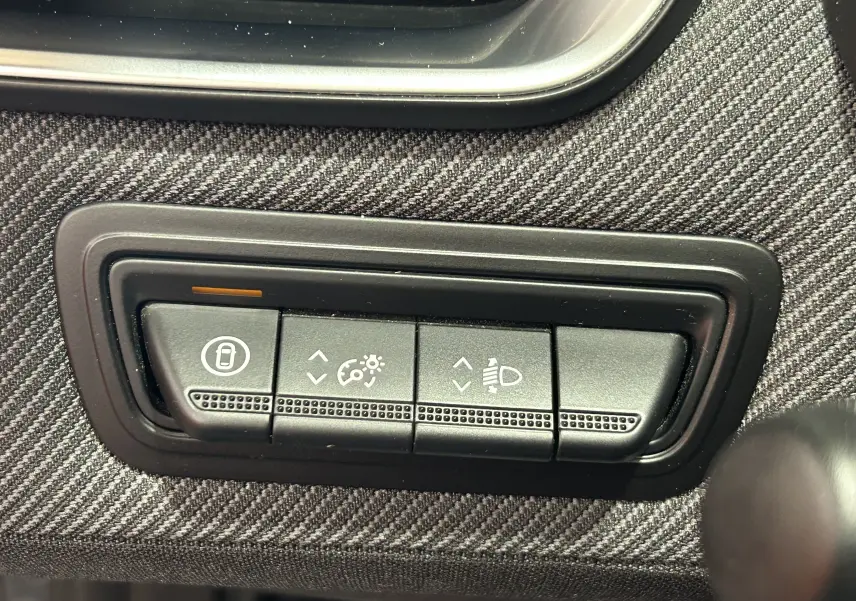 Gros plan sur les commandes de réglage des phares et du tableau de bord du Renault Clio V gris schiste.