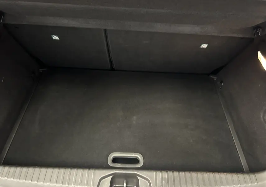 Vue intérieure du coffre vide de la Renault Clio V TCe 90 Esprit Alpine, avec revêtement noir et éclairage latéral.