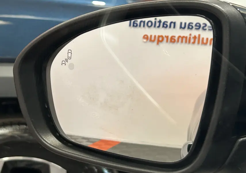 Rétroviseur extérieur côté droit de la Renault Clio V gris schiste, avec icône d’alerte d’angle mort visible.