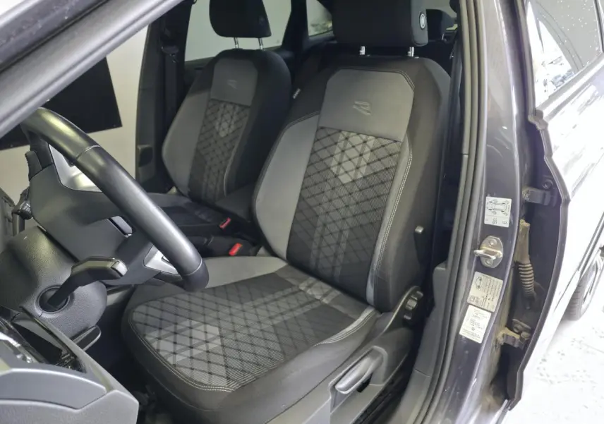 Vue intérieure côté conducteur du Volkswagen Taigo gris foncé, sièges sport R-Line en tissu avec motifs géométriques.