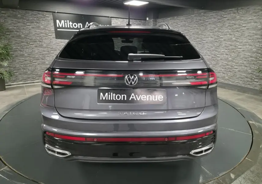 Vue arrière d'un Volkswagen Taigo gris foncé avec feux LED reliés par une baguette lumineuse et double sorties d'échappement chromées.