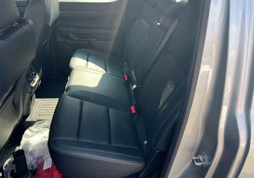 Vue côté droit de la banquette arrière en cuir noir du Ford Ranger 2025 gris iconic avec ceinture rouge visible.