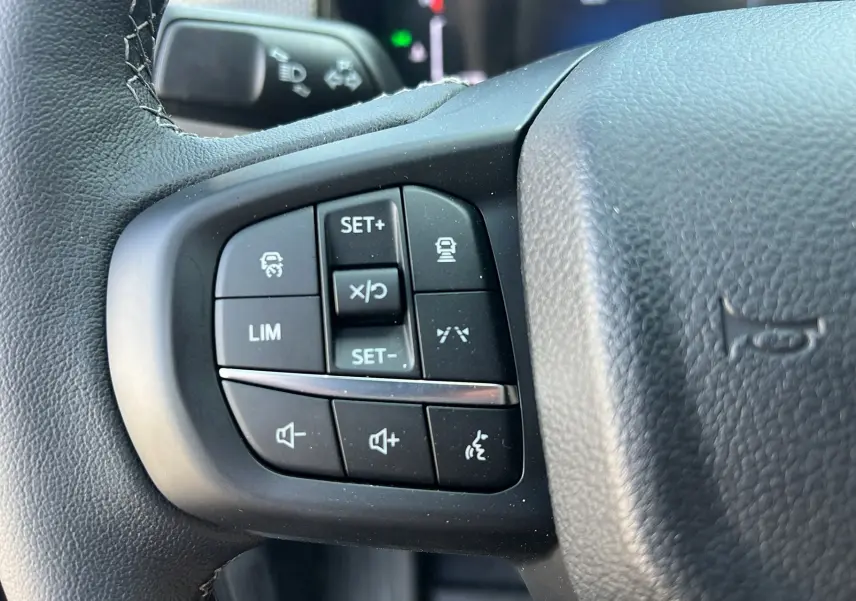 Gros plan sur les commandes multifonctions à gauche du volant cuir du Ford Ranger gris iconic 2025.
