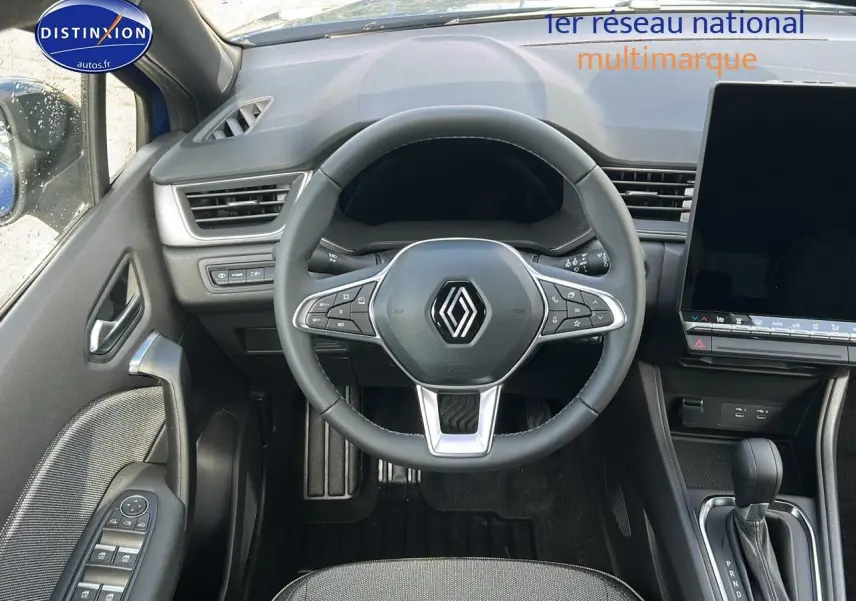 Vue intérieure centrée sur le volant multifonction du Renault Captur bleu iron, avec écran tactile et levier de vitesses automatique visible.