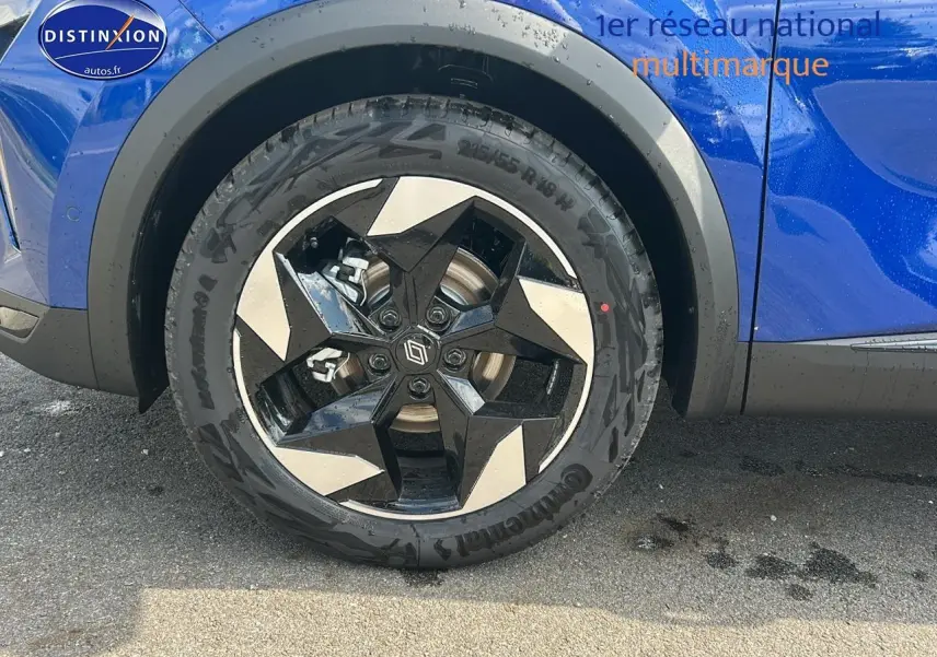 Gros plan sur la roue avant gauche du Renault Captur bleu iron, mettant en valeur la jante alu au design géométrique.