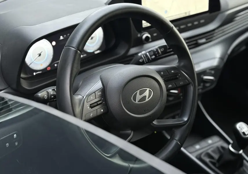 Vue rapprochée du volant cuir noir et du tableau de bord numérique de la Hyundai i20 2025 avec écran tactile GPS.