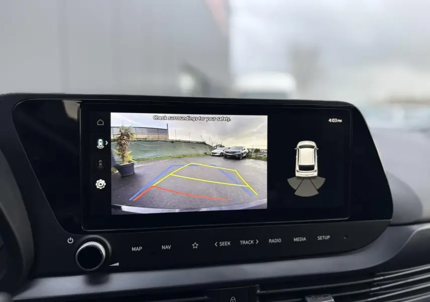 Vue rapprochée de l'écran tactile intérieur affichant la caméra de recul et l'aide au stationnement du Hyundai i20 noir Phantom Metal.