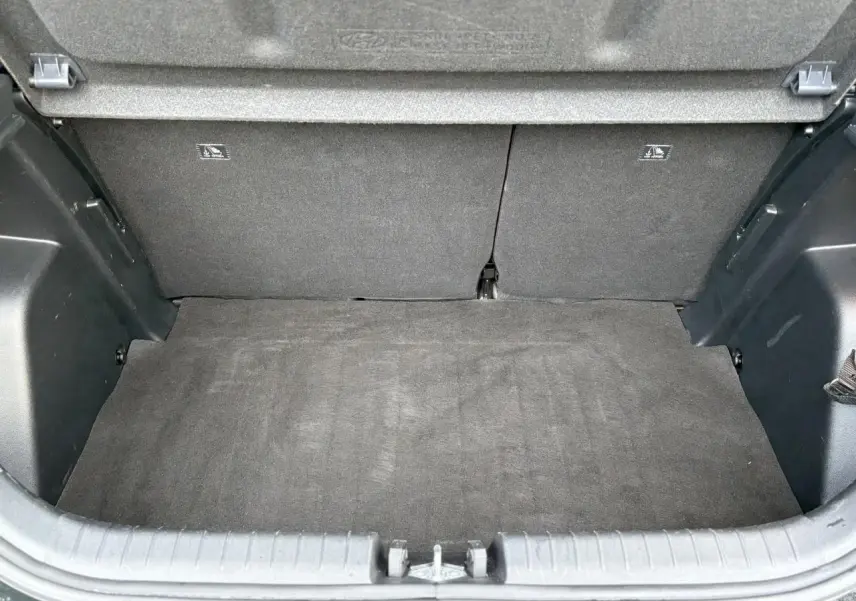 Vue du coffre ouvert d'une Hyundai i20 2025 noir Phantom Metal, montrant l'espace de chargement vide et la moquette intérieure.