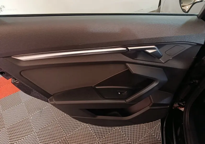 Vue intérieure côté gauche de la porte noire d'une Audi A3 35 TDI 150 S tronic Business Line avec poignée argentée.