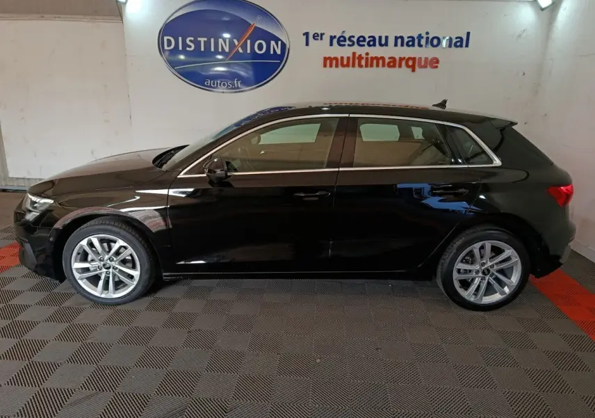 Audi A3 35 TDI Business Line noire vue de profil côté gauche dans un showroom avec logo Distinxion en arrière-plan.