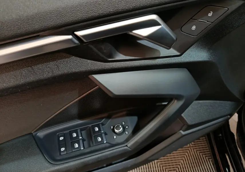 Gros plan sur la porte avant gauche noire de l'Audi A3 35 TDI 2023 avec commandes des vitres et serrure.