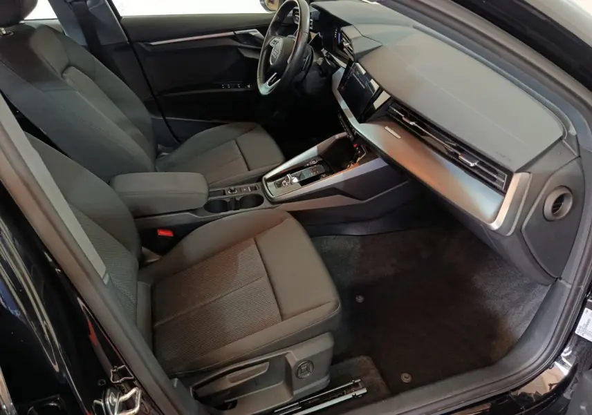 Vue intérieure côté conducteur de l'Audi A3 35 TDI 2023 noire, avec tableau de bord moderne et sièges tissu gris.
