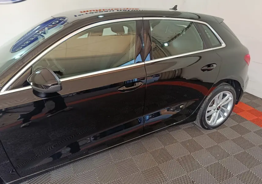 Vue latérale gauche d'une Audi A3 noire 2023 avec jantes alliage et rétroviseur noir brillant.