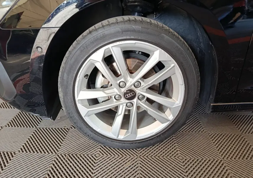 Gros plan sur la roue avant gauche avec jante argentée et logo Audi sur une Audi A3 noire 2023.