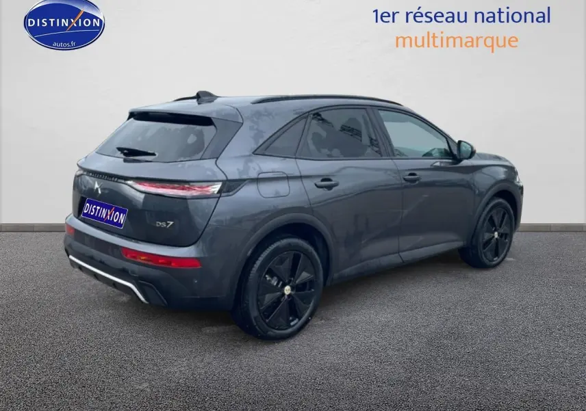 Vue 3/4 arrière droite d’un DS7 gris titane avec jantes noires et feux arrière LED allumés.