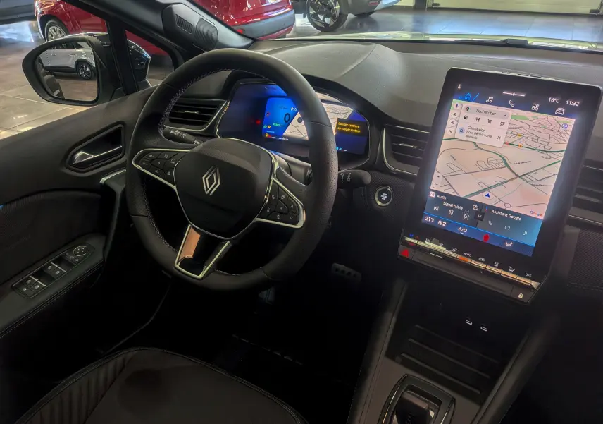 Vue intérieure côté conducteur du Renault SYMBIOZ E-TECH avec volant multifonction et grand écran tactile vertical.