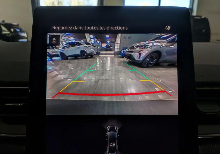 Vue de la caméra de recul du Renault Symbioz blanc nacré, affichant les lignes d’aide au stationnement en intérieur.