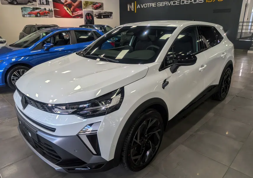 Renault Symbioz blanc nacré en 3/4 avant droit, avec jantes noires et détails noirs contrastants visibles en showroom.