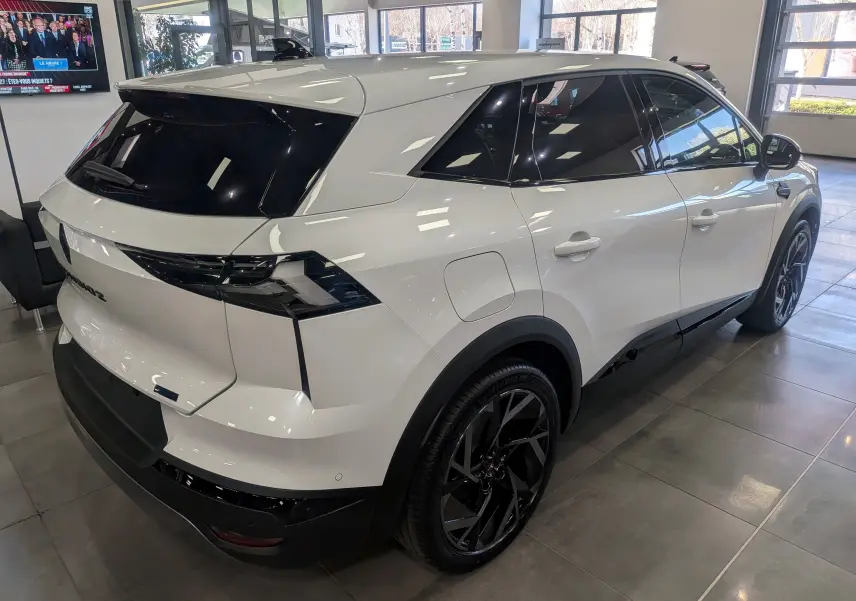 Vue 3/4 arrière droite du Renault SYMBIOZ blanc nacré, avec vitres teintées et jantes noires distinctives.