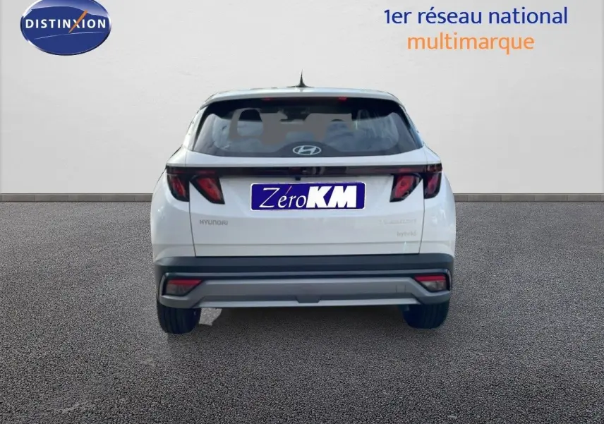 Vue arrière d'un Hyundai Tucson blanc Atlas 2026 avec feux arrière sombres et logo Hyundai visible.