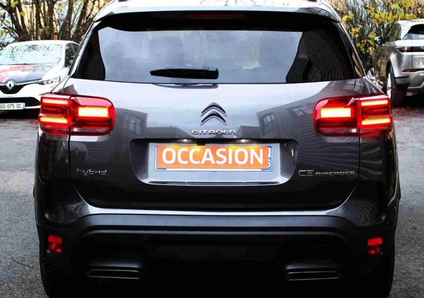 Vue arrière d'un Citroën C5 Aircross gris platinium hybride rechargeable avec feux arrière allumés et plaque "OCCASION".