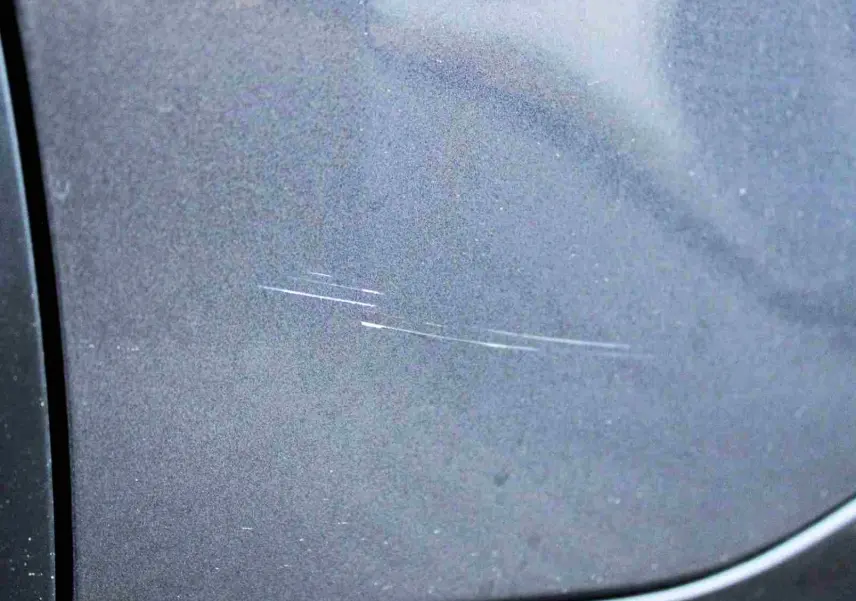 Gros plan sur une rayure fine sur la porte côté gauche d'un Citroën C5 Aircross gris platinium hybride rechargeable.