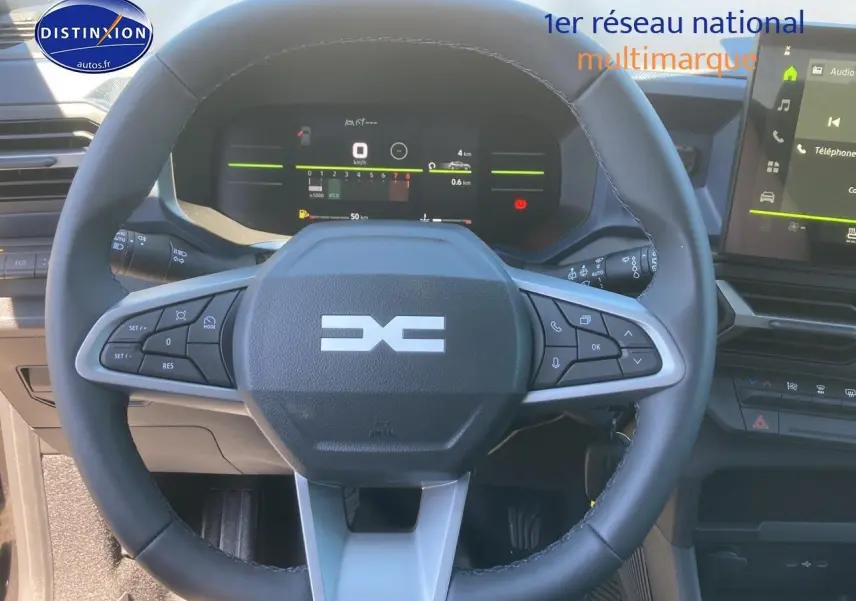 Vue rapprochée du volant multifonction noir et gris du Dacia Duster 2025 avec tableau de bord numérique et écran tactile.