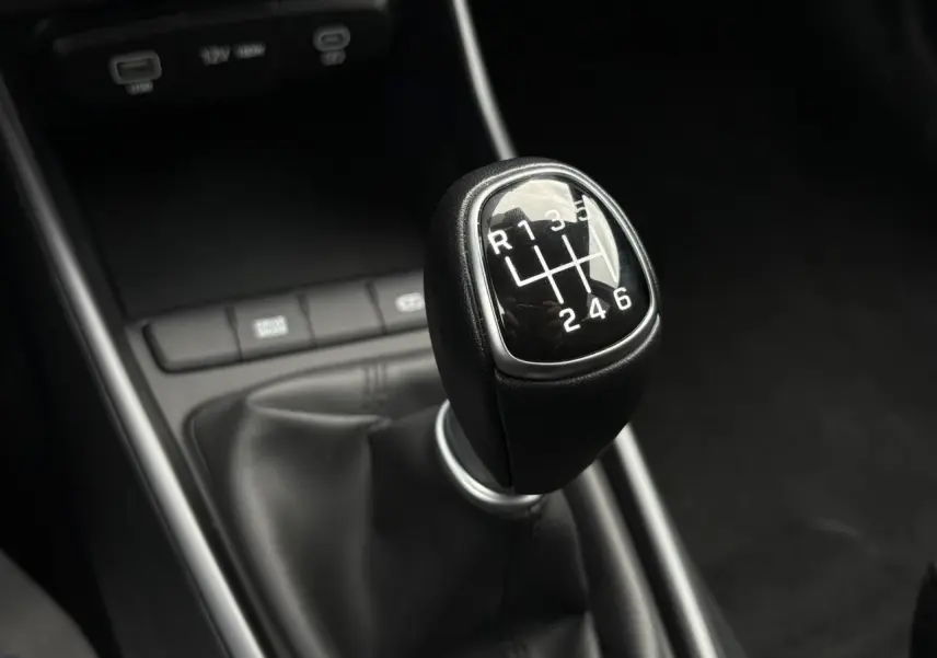Gros plan sur le levier de vitesses manuel noir de la Hyundai i20 2025, intérieur sobre et moderne.