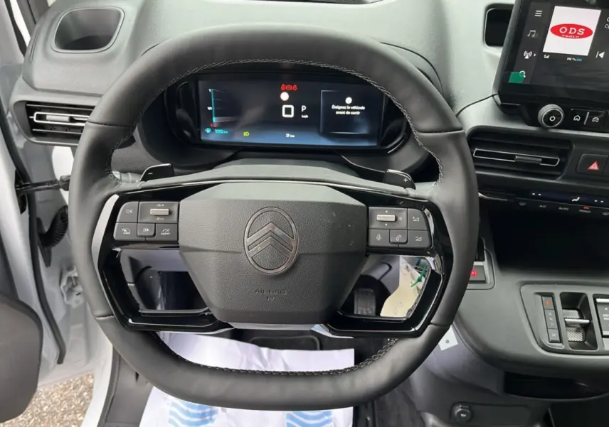 Vue intérieure centrée sur le volant cuir multifonctions du Citroën Berlingo blanc, avec tableau de bord numérique et écran tactile.