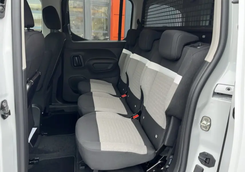 Vue latérale intérieure du Citroën Berlingo Kaolin White montrant les trois sièges arrière indépendants en tissu gris et noir.