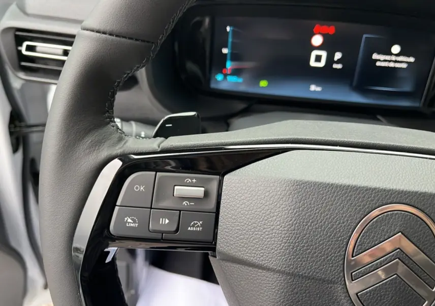 Gros plan sur le volant cuir multifonctions gris du Citroën Berlingo 2026 avec commandes intégrées et tableau de bord numérique flou.