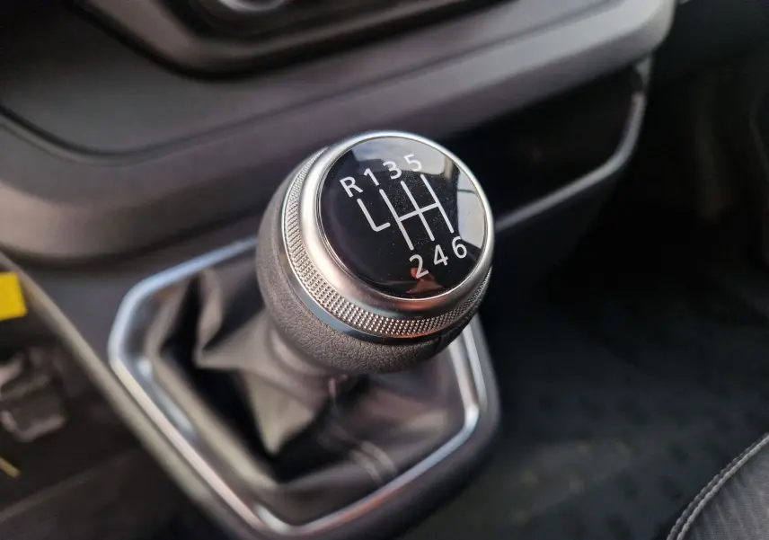Gros plan sur le levier de vitesses manuel noir du Nissan Primastar 2025, montrant les six rapports et la marche arrière.