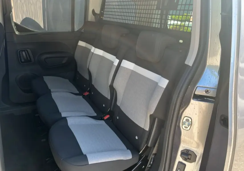 Vue latérale du siège arrière gris clair et noir du Citroën Berlingo 2025 avec grille de séparation métallique.