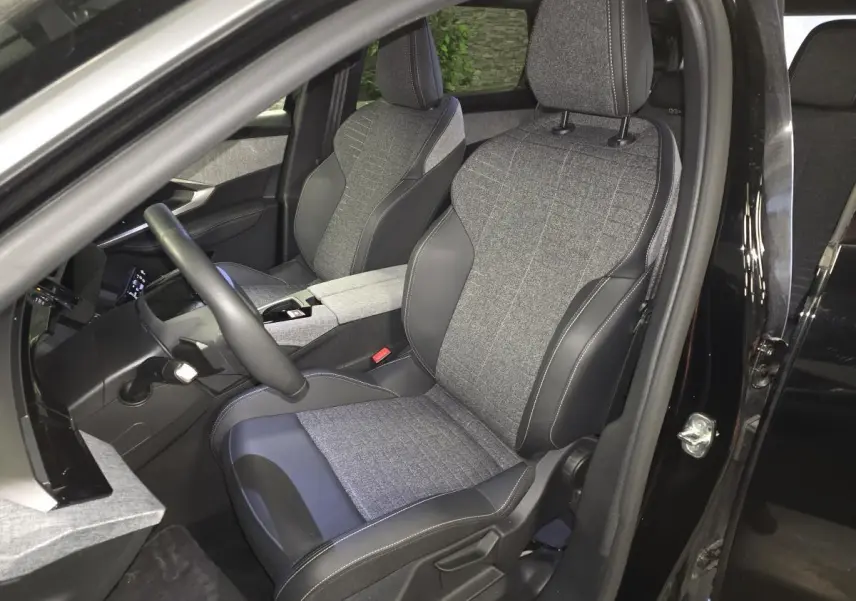 Vue intérieure côté conducteur du Peugeot 5008 noir 2025, sièges tissu gris et cuir noir avec surpiqûres quartz.