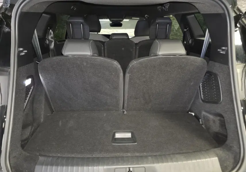 Vue arrière du coffre noir du Peugeot 5008 2025 avec sièges rabattus et habillage intérieur sombre.