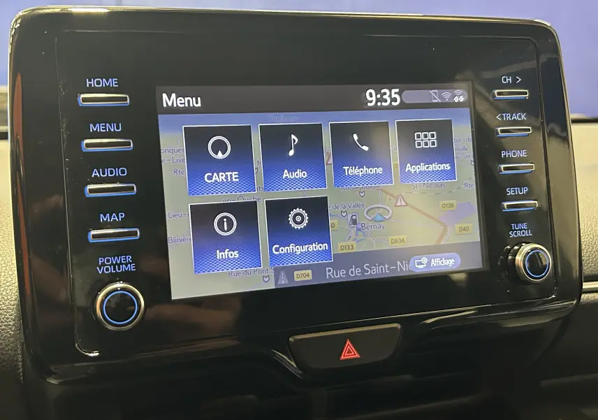 Écran tactile central de la Toyota Yaris 116h blanc, affichant le menu GPS avec boutons latéraux et bouton d’alerte en dessous.
