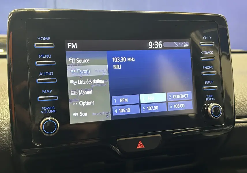 Écran tactile central de la Toyota Yaris 116h blanc, affichant la radio FM NRJ à 9h36 avec commandes autour.