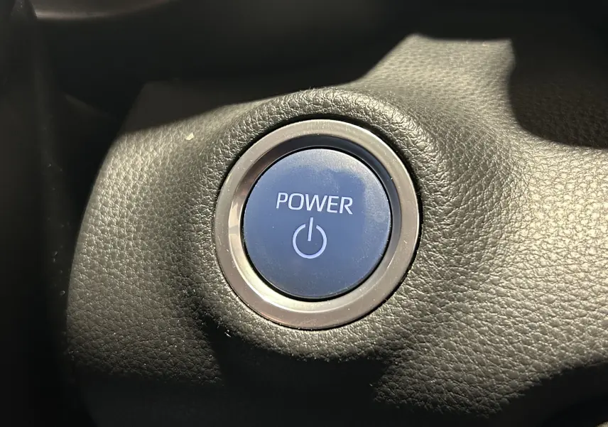 Gros plan sur le bouton start/stop bleu entouré de noir dans l’habitacle de la Toyota Yaris hybride blanche 2021.